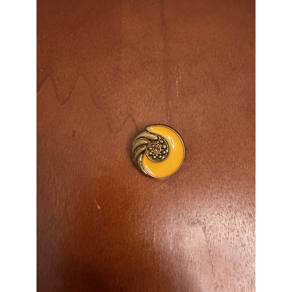 decorative button or brooch featuring a gold-toned metallic nautilus Shell